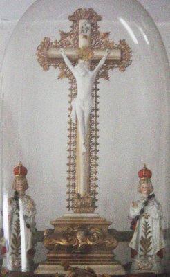 Sous un globe, un Christ en croix est entouré de statuettes de l'Enfant Jésus de Prague